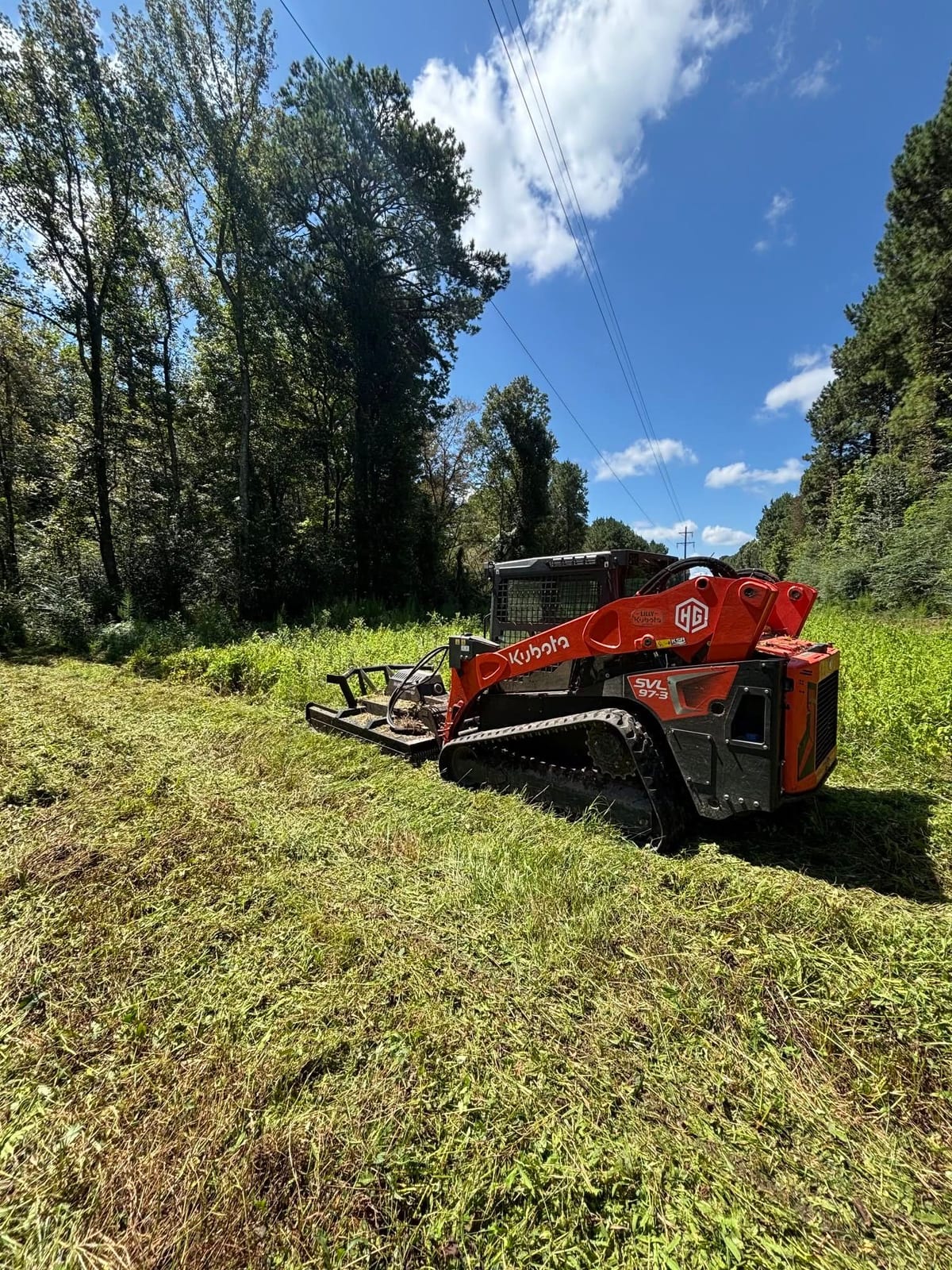Red track loader with mulching head cutting through brush in North Mississippi