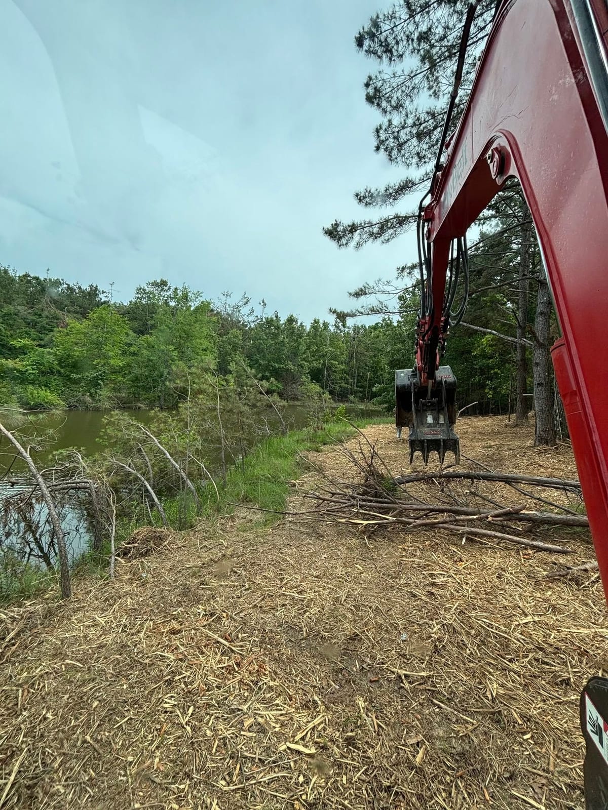 Excavator cleanup on a pond bank — Property Cleanup in North Mississippi